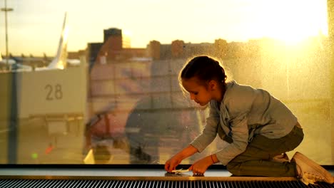 Little-kid-playing-with-small-model-airplane-in-airport-waiting-for-boarding