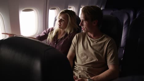 Couple-talking-and-looking-out-window-on-airplane-flight