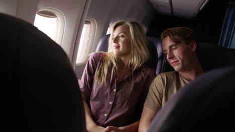 Couple-talking-and-looking-out-window-on-airplane-flight