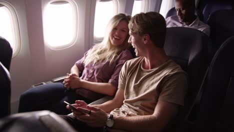 Couple-looking-at-mobile-phone-together-on-airplane-flight