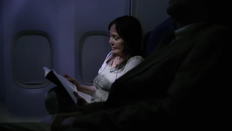 Mujer-leyendo-por-la-noche-en-vuelo-de-avión