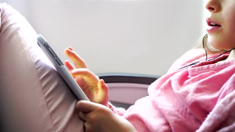 Adorable-little-girl-traveling-by-an-airplane.-Cute-kid-with-laptop-near-window-in-aircraft