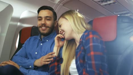 Auf-einem-kommerziellen-Flug-erzählt-Hispanic-Mann-seine-schöne-Blonde-Freundin-lustige-Geschichte.-Beide-lachen.-Sie-Reisen-im-neuen-Flugzeug.