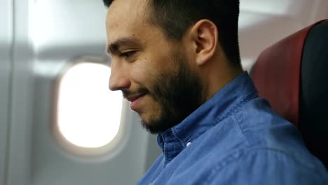 On-a-Board-of-Commercial-Airplane--Handsome-Hispanic-Male-Works-on-His-Laptop.-Sun-Shines-Through-Aeroplane-Window.