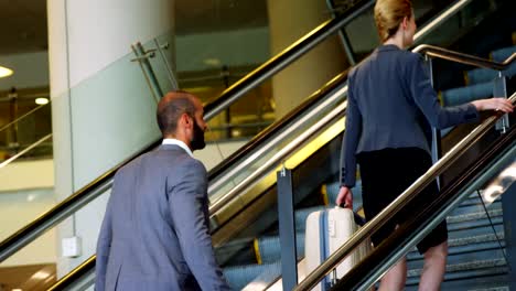 Businessman-and-woman-climbing-staircase-with-luggage