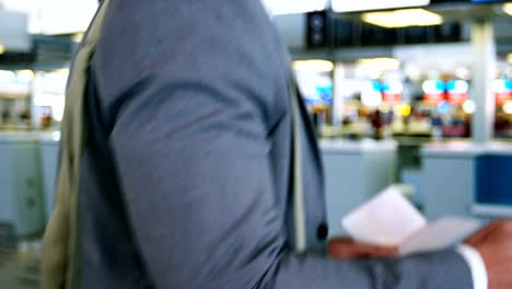 Businessman-using-mobile-phone-while-checking-his-boarding-pass