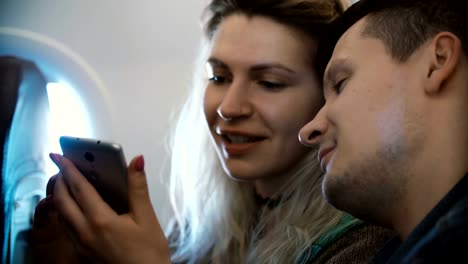 Junge-schöne-paar-Reisen-mit-dem-Flugzeug.-Blonde-Frau-und-Mann-unter-Selfie-Foto-auf-Smartphone-neben-dem-Fenster