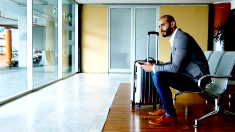 Businessman-texting-on-mobile-phone-at-airport