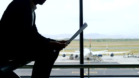 Geschäftsmann-am-Flughafen-sitzen-und-Zeitung-lesen