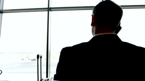 Businessman-talking-on-mobile-phone-at-airport