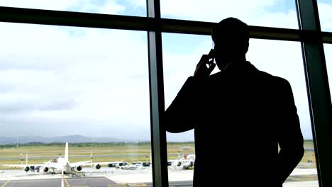 Businessman-talking-on-mobile-phone-at-airport