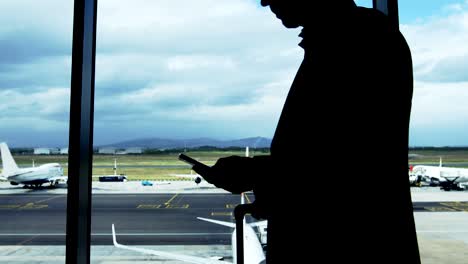 Businessman-texting-on-mobile-phone-at-airport