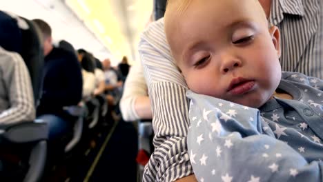 Tired-toddler-in-the-plane-at-the-mother's-lap