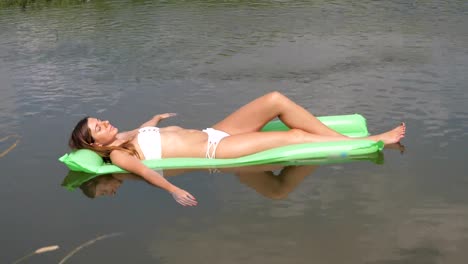 Closeup-junge-Frau-im-weißen-Badeanzug-Sonnenbaden-Handauflegen-Matratze-im-Wasser