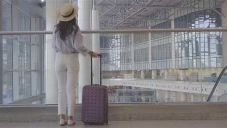 Young-woman-with-baggage-in-international-airport-walking-with-her-luggage.-Airline-passenger-in-an-airport-lounge-waiting-for-flight-aircraft