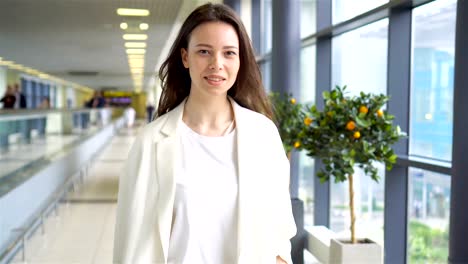 Mujer-joven-con-el-equipaje-en-el-aeropuerto-internacional-de-caminar-con-su-equipaje.-Pasajeros-de-la-aerolínea-en-un-salón-del-aeropuerto-esperando-el-avión-de-vuelo.