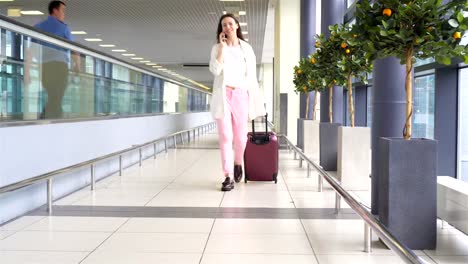 Young-woman-with-baggage-in-international-airport-walking-with-her-luggage.-Airline-passenger-in-an-airport-lounge-waiting-for-flight-aircraft.