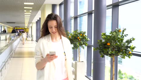 Young-woman-with-smartphone-in-international-airport.-Airline-passenger-in-an-airport-lounge-waiting-for-flight-aircraft