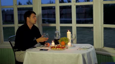 Man-Sits-in-the-Restaurant-On-the-Veranda-Drinking-Wine-That-Comes-a-Woman