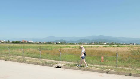 Young-girl-walks-along-the-barbed-fence-of-airport.-Batumi,-Georgia