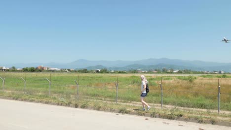 Young-girl-walks-along-the-barbed-fence-of-airport.-Batumi,-Georgia