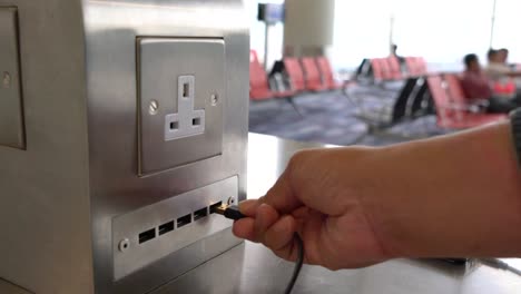 Traveler-charging-mobile-phone-battery-at-free-service-charging-station-at-International-Airport.