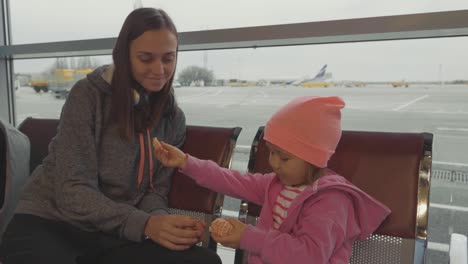 Madre-e-hija-en-el-aeropuerto.-Mandarín-de-niña-en-sala-de-espera.