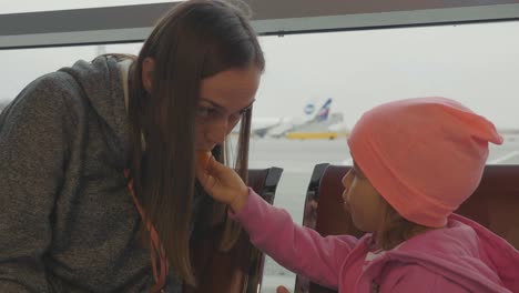 Madre-e-hija-en-el-aeropuerto.-Mandarín-de-niña-en-sala-de-espera.