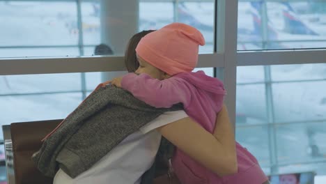 Joven-madre-e-hija-poco-Linda-abrazan-suavemente-en-el-aeropuerto-en-cámara-lenta.