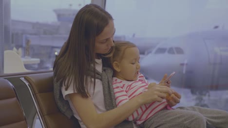 Mother-feeds-her-little-daughter-with-tangerine-at-airport-in-slow-motion