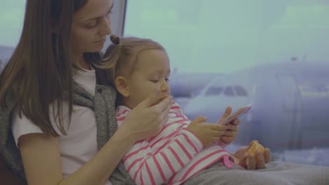 Mother-feeds-her-little-daughter-with-tangerine-at-airport-in-slow-motion