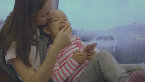 Mother-feeds-her-little-daughter-with-tangerine-at-airport-in-slow-motion