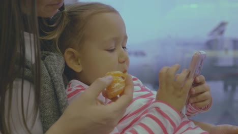 Mother-feeds-her-little-daughter-with-tangerine-at-airport-in-slow-motion