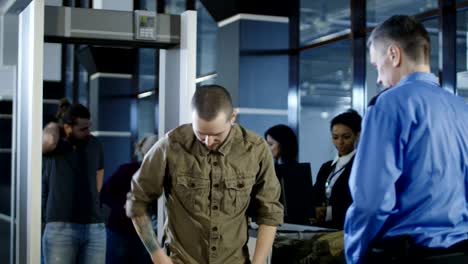 Airport-worker-checking-passenger-with-metal-detector