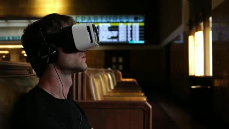 Young-man-wearing-virtual-reality-headset-watching-360-video-in-train-union-station