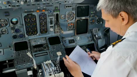 Captain-of-airplane-prepares-documents-before-flight-sitting-in-cockpit