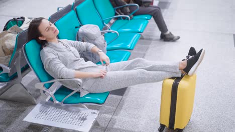 Schöne-Frau-mit-kurzen-Brünette-Haare-liegen-in-einem-Sitze-mit-ihren-Beinen-auf-einem-Gepäck