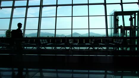 Silhouetten-von-Reisenden-in-einem-geschäftigen-Flughafen-terminal-gegen-Glas-Wand-Fenster