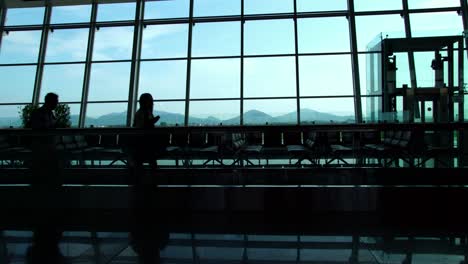 Silhouette-der-Passagiere-zu-Fuß-in-der-belebten-internationalen-terminal-Halle-am-Flughafen