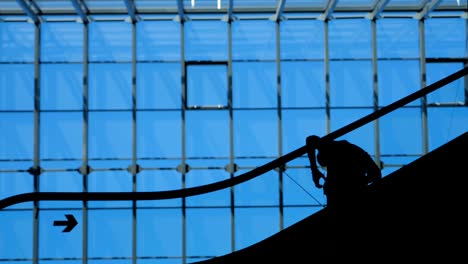 Modern-glass-building-and-moving-silhouettes-of-business-persons-on-escalator