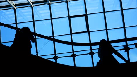 Modern-glass-building-and-moving-silhouettes-of-business-persons-on-escalator