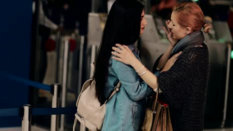 Mother-and-young-daughter-embracing-and-saying-goodbye-at-airport
