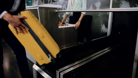 Young-man-weighing-suitcase-and-doing-check-in-at-airport