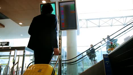 Young-businessman-looking-at-airport-departure-board-before-flight