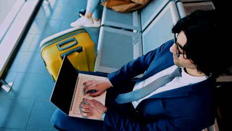 Young-businessman-using-laptop-while-waiting-to-board-on-airplane