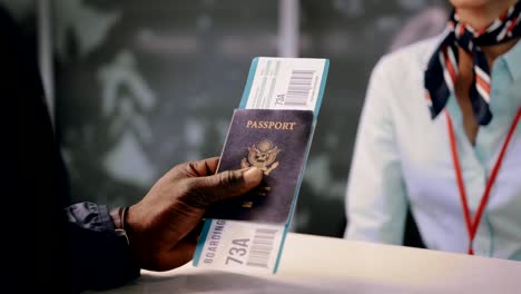 Flight-passenger-holding-passport-and-boarding-pass-at-airline-desk