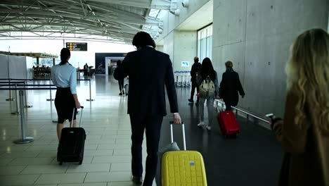 Multi-ethnic-travelers-walking-on-airport-corridor-towards-gate