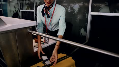 Young-airline-attendant-attaching-label-on-traveler's-suitcase