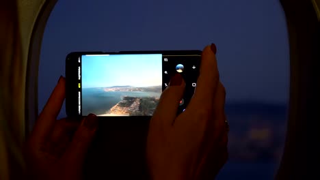 Close-up-woman-hand-holding-mobile-phone-and-take-a-photo-outside-airplane-window