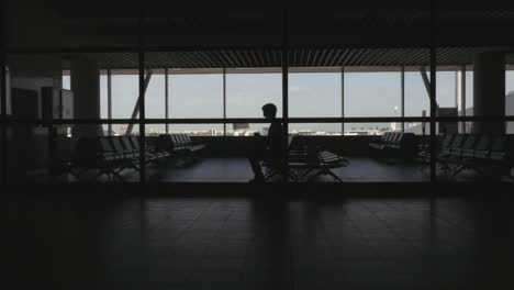 Silueta-de-pasajeros-en-un-aeropuerto-esperando-área-y-navegación-por-Internet